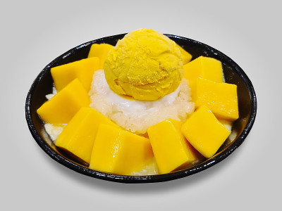 一碗用糯米和芒果块隔开的黄色芒果冰淇淋勺