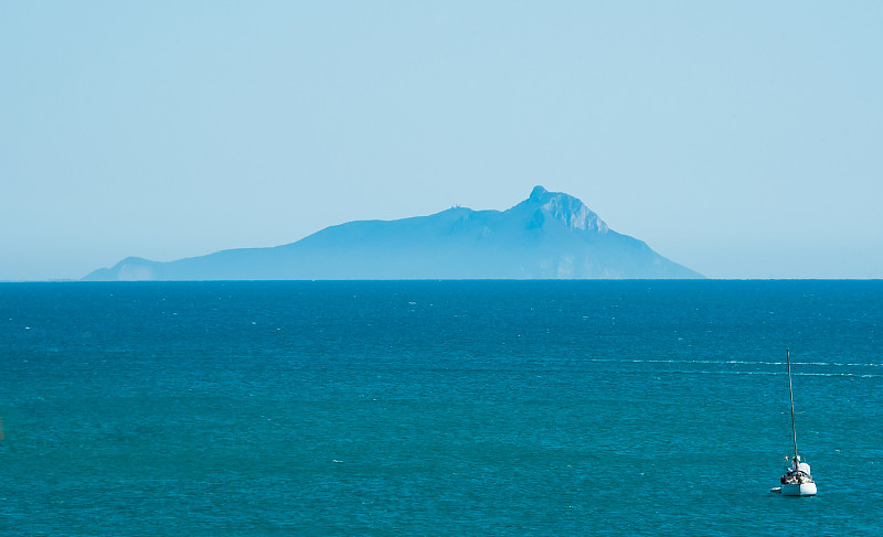 地平线上的岛屿和海上的帆船