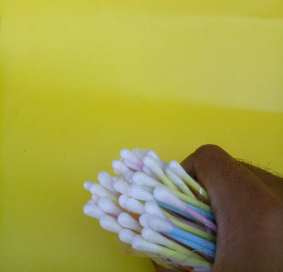 手拿棉花梳耳清洁剂孤立在黄色背景上