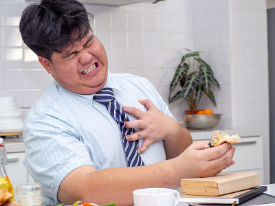 亚洲胖男人吃东西时感到心痛。心脏病发作，胸痛的男人。