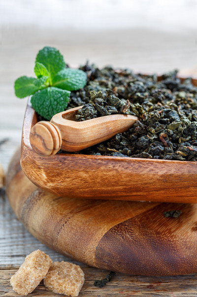 棕色木碗中放入绿茶和薄荷枝。