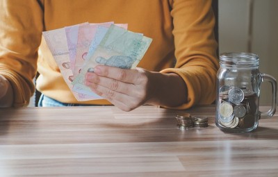 年轻美丽的亚洲女子手持钞票在家，概念金融企业投资物业。