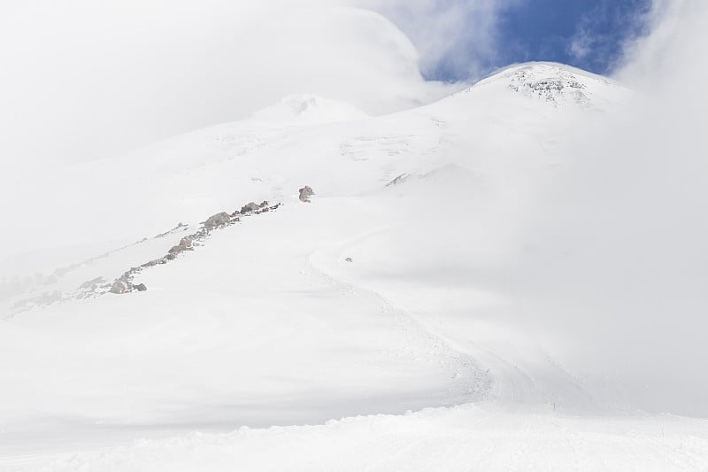 在雪天和雾天的两个厄尔布鲁斯山峰的全景。山徒步旅行