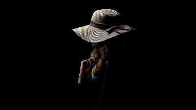 Anonymous lady in hat holding hair, hiding face fr