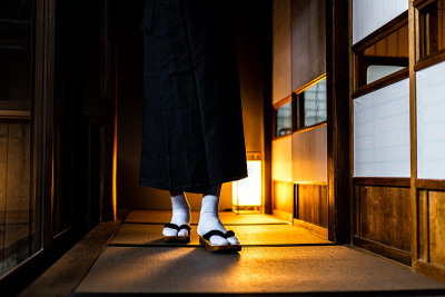传统的日本房子或日式客栈，男人穿着和服走路的腿部特写，脚上穿着一双大扁鞋和白袜子，旁边是shoji滑