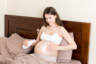 孕妇在腹部涂抹妊娠纹霜。怀孕，人与孕的观念。孕妇在腹部涂抹抗妊娠纹霜