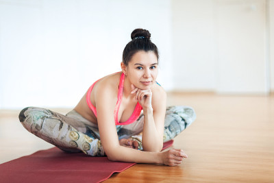 一个快乐的女人的肖像黑发运动看起来坐在地毯前锻炼