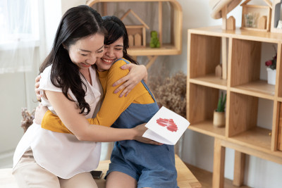 幸福的亚洲家庭妈妈和十几岁的女儿拥抱在一起，在一个房间的自然阳光在家。展示爱心，母亲节快乐的理念