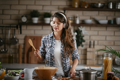 年轻女子在厨房里准备食物和听音乐