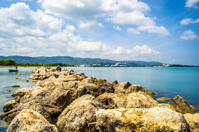 从牙买加蒙特哥湾的北海岸风景优美的海水景观设置，有巨大的海巨石和邮轮和山脉的背景。