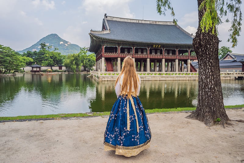 身穿韩服的年轻白种女游客在韩国宫殿。韩国旅游概念。国家韩国的服装。为游客提供的娱乐——试穿韩国民族服