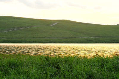夕阳的光芒反射在湖面上，湖面被高山环绕。