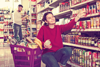 一对夫妇站在商店里放着罐头食品的货架旁