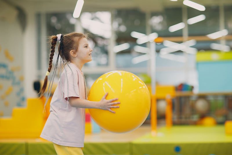 幼儿园或小学的小女孩在体育馆用大球玩耍和做运动。儿童运动健身理念。