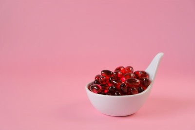 磷虾油胶囊在一个陶瓷勺子在浅粉红色的背景。天然补品和维生素。欧米茄脂肪酸。健康饮食和食品补充