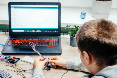 一个男孩在学习arduino编程和机器人技术时，正在为传感器芯片插电缆
