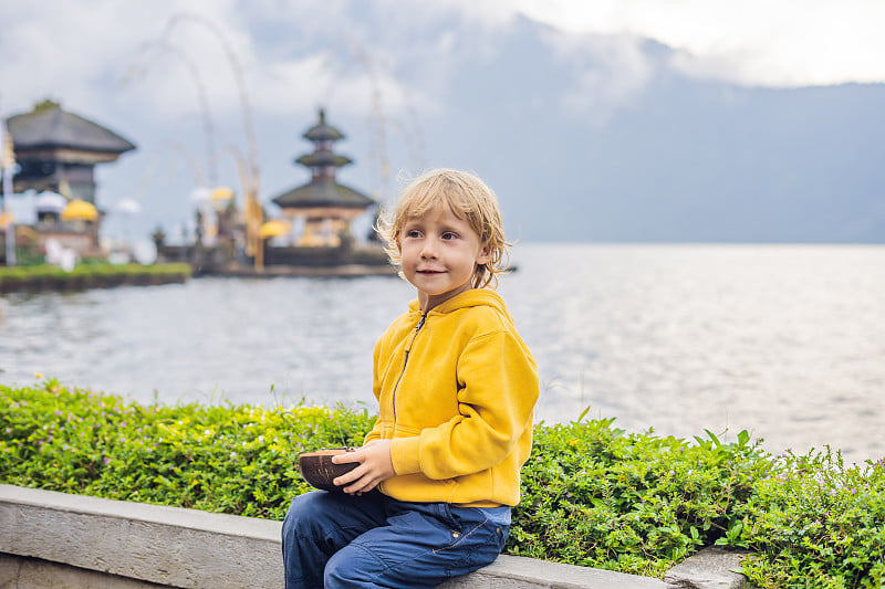 男孩旅行者在Pura Ulun Danu Bratan的背景，巴厘岛。巴厘岛Bratan湖上被鲜花环