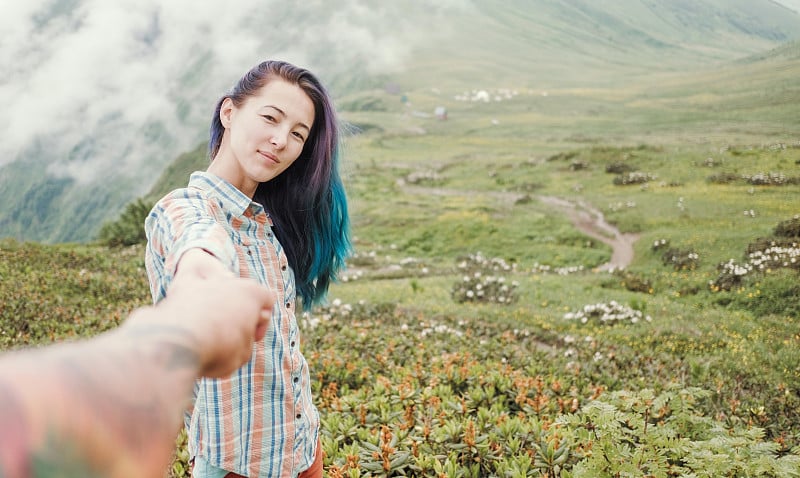 年轻的女人牵着男人的手，带领他在夏天的山，波夫。跟我来。