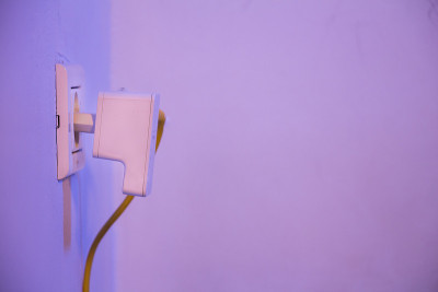 WiFi扩展器插在墙上的电源插座上，插着以太网线
