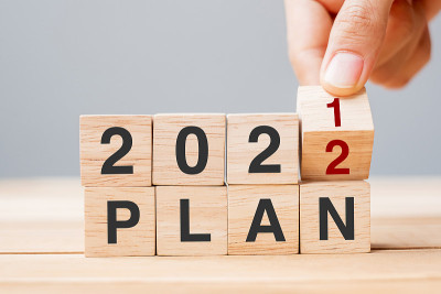 商人手握木立方体和翻转块2021至2022计划在桌子背景。决心，目标，回顾，改变，开始和新年假期的概