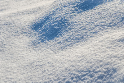 在一个阳光明媚的日子里，花园里山坡上覆盖着一层新雪。冬季自然背景。