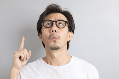 亚洲男人戴着眼镜，灰色背景上带着惊讶和惊奇的表情。