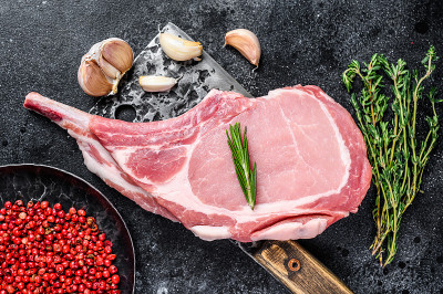 用切肉刀切生的战斧猪排。黑色背景。俯视图