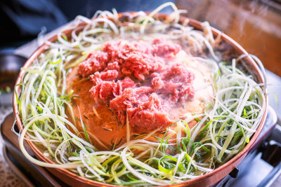 牛肉烧烤韩式烤肉在首尔的韩国餐厅，生活方式新鲜的韩国菜烹饪铜锅与切片烧烤，近距离，拷贝空间