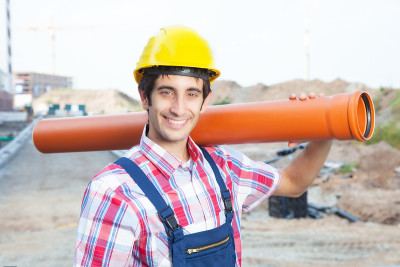 快乐的西班牙建筑工人在建筑工地拿着管子