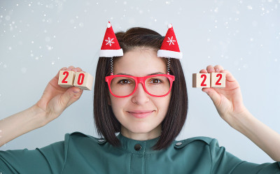 一个戴着搞笑新年眼镜的小女孩手里拿着数字为2022的立方体。