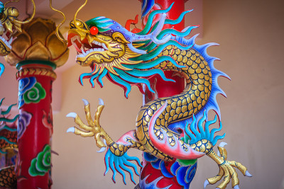 五颜六色的中国龙绕红柱雕像。在中国公共寺庙中，寺庙柱周围雕刻着美丽的龙像。