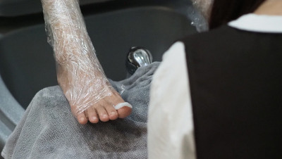 脚Spa。在水疗店的肥皂水机里，女人光脚按摩。女人的脚进入脚浴在热水手持式。在水疗沙龙用脚油按摩。放