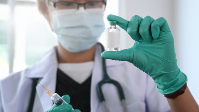 女医生戴着防护口罩，手持药物疫苗站在医院的特写手。