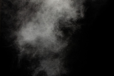 白色粉末爆炸云在黑色背景下。白色灰尘颗粒飞溅。