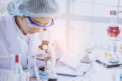 女科学家在实验室研究实验生物技术中通过显微镜、科学试管分析科学样本培育抗病毒疫苗。化学科学实验室概念
