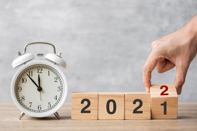 新年快乐，老式闹钟和手翻转2021年改为2022块。圣诞节，新的开始，决心，倒计时，目标，计划，行动