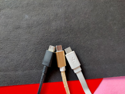 三根白色，黑色，金色的微型USB线。孤立在黑色背景上，