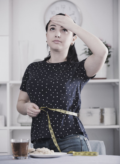 沮丧的女孩测量腰围