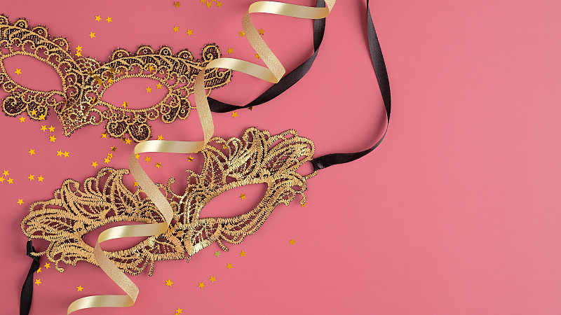 Masquerade golden masks and confetti on pink backg