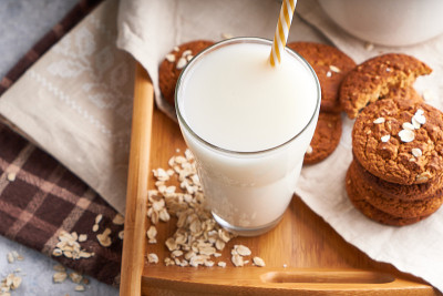 健康的替代牛奶。自制燕麦牛奶在玻璃和瓶子轻桌上不含乳糖特写