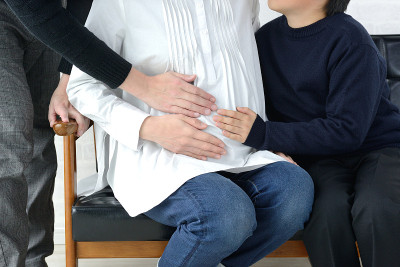 孩子和父亲在客厅触摸孕妇的肚子