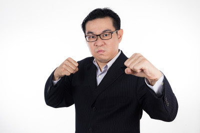 愤怒的亚洲华人穿着西装，双手紧握拳头