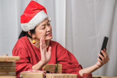 亚洲妇女戴圣诞帽视频电话聚会与朋友与移动电话桌上在家里