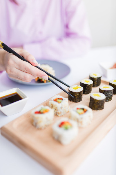 女人用筷子手拿着寿司卷。健康海鲜亚洲日本料理。