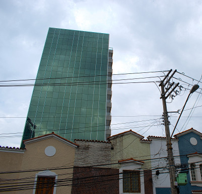对比建筑，与阴天，反光建筑玻璃面板和窗户，与老房子的前景，在圣保罗，巴西。