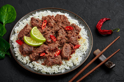 牛肉仁当放在黑色的盘子上，放在黑色的石板桌上。印尼巴东菜荤菜。亚洲食品。