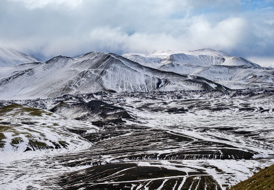 冰岛南部高地的季节变化。秋天冰雪覆盖下多彩的曼那洛格山脉。