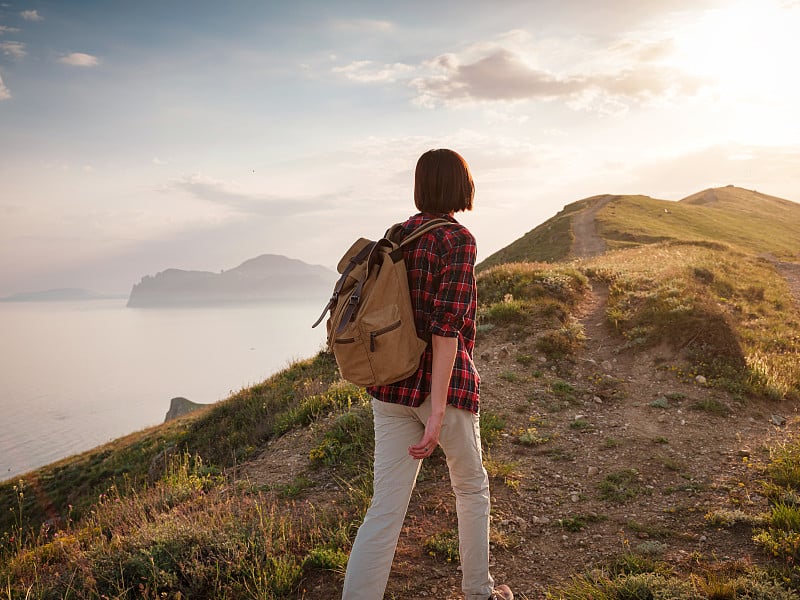 一个年轻的亚洲女人背着背包在夏天徒步旅行。