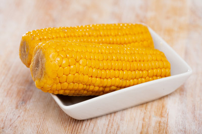 美味的甜煮玉米棒在盘子里。健康食品的概念