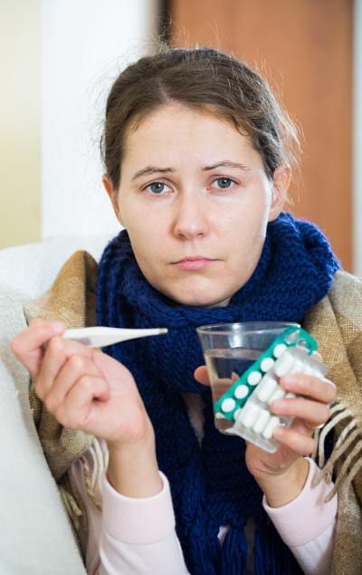 褐发女人在家里的毯子下发烧